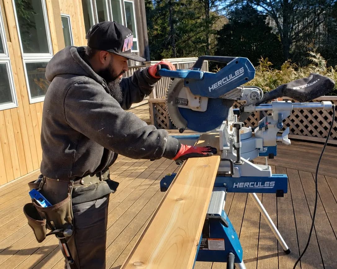 CHOY CONSTRUCTION carpenter cutting lumber with a miter saw.